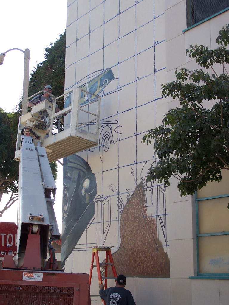 Day 3: Photograph of Dennis McGonagle taking the boom lift up to work on the Chevy car section of the mural.