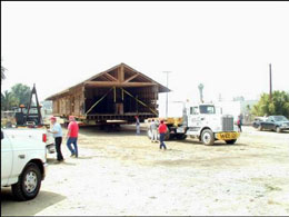 Photograph of the warehouse unit of the Southern Pacific depot being pulled by a semi-truck