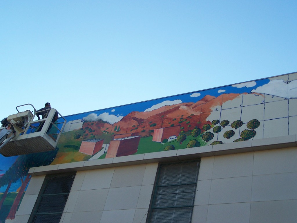 Day 8: Tyler Kinnaman shown on the boom lift just starting the Whittier College section of the mural.