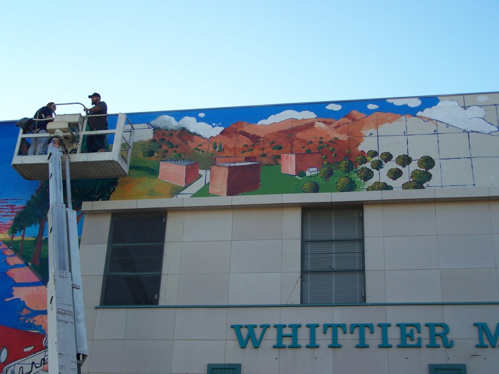 Day 8: Dennis McGonagle and Tyler Kinnaman shown on the boom lift just starting the Whittier College section of the mural.