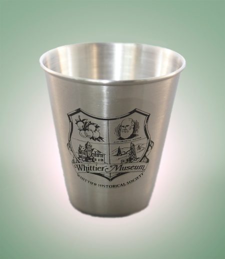 Photograph of stainless steel shot glass with the Whittier Historical Society coat of arms printed in black.