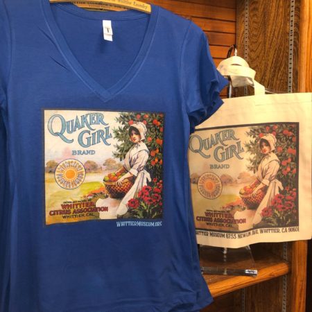 Photograph of Quaker Girl t-shirt. The t-shirt is a deep v-neck with short sleeves. The color is royal blue and the fruit label graphic is on the front of the shirt.