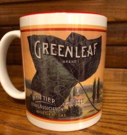 Photograph of coffee mug with Greenleaf Brand graphic on the front. Mug has white background and red color on the interior of the mug.