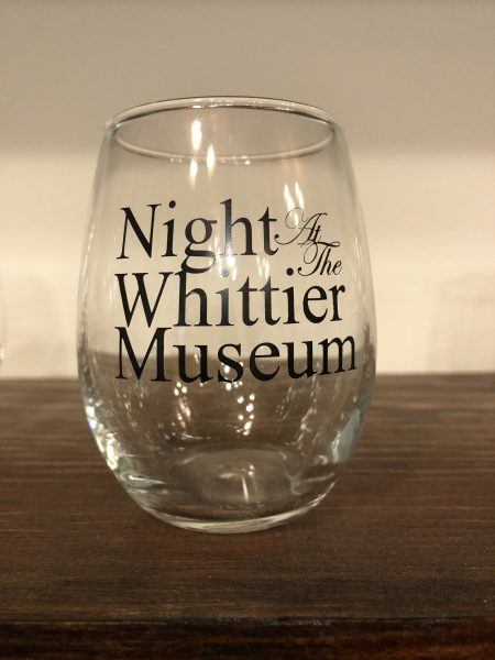Photograph of stemless wine glass. Text in black printed on glass "Night at the Whittier Museum"
