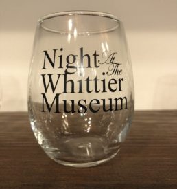 Photograph of stemless wine glass. Text in black printed on glass "Night at the Whittier Museum"