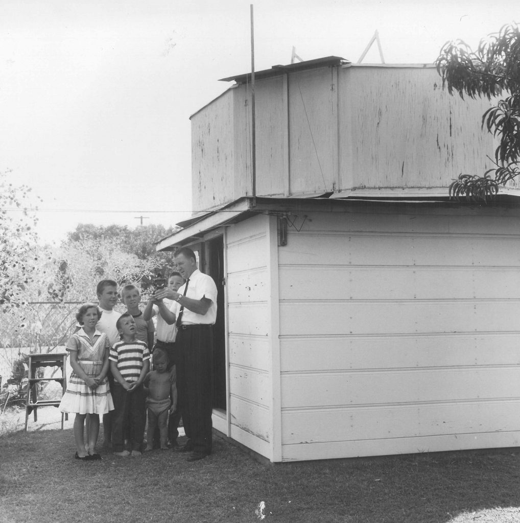 Photo. Nemecek's backyard shed home observatory.  He is explaining something to a group of rapt children.
