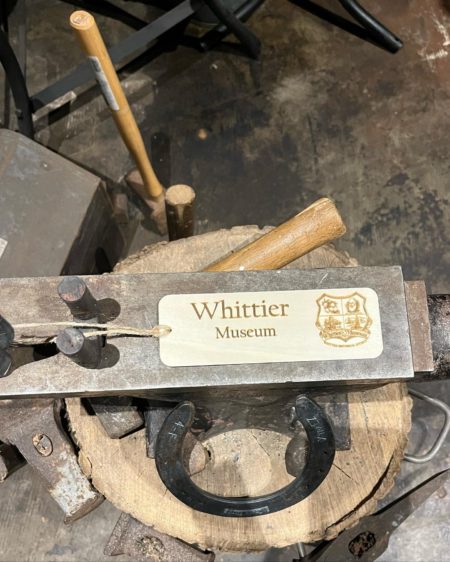 Photograph of thin, wood bookmarker with text "Whittier Museum" and the Whittier Historical Society coat of arms.