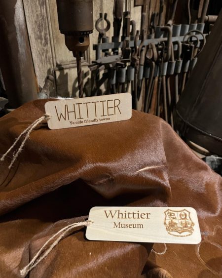 Photograph of two thin, wood book marks. Text on first "Whittier Ye olde friendly towne" and text on second "Whittier Museum" and includes Whittier Historical Society coat of arms.