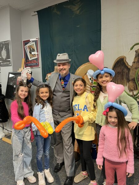 Magician "Professor Hogwarts" with kids performing balloon magic on opening day of the magic exhibit.