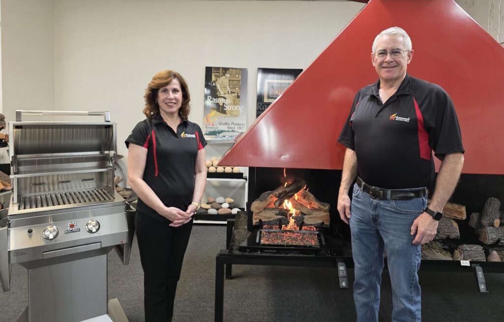 Irene and Rett Rasmussen in the showroom with a Solaire grill and gas log set.